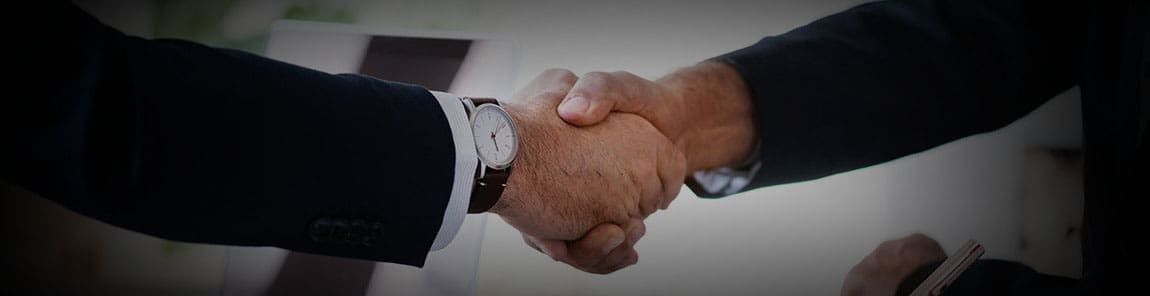 Two people shaking hands over a white surface.